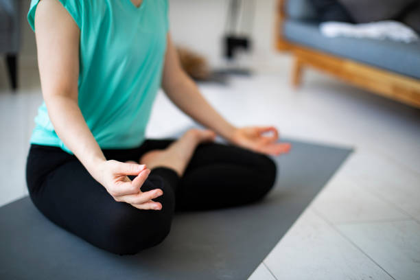 istock Young woman practicing yoga at home with laptop during quarantine 1254288572
