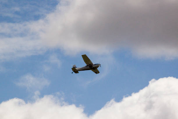 istock LITTLE WHITE PLANE, FLYING IN THE BLUE SKY WITH WHITE CLOUDS ON THE SIDES, 1254292021