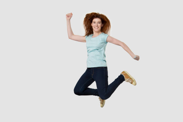 istock Overjoyed young happy red-haired woman jumping high. 1254296699