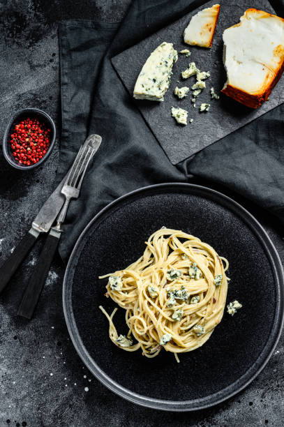 istock Spaghetti pasta with blue Gorgonzola cheese sauce. Black background. Top view. 1254298802