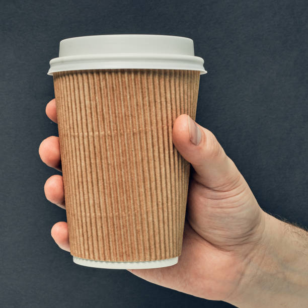 istock Paper cup in hand on a colored background. Eco-friendly materials in a coffee shop, biodegradable disposable tableware. Close up 1254302368