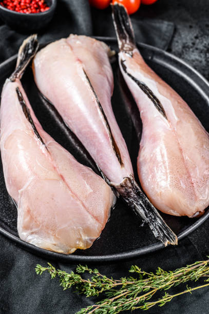 istock Separate raw fish monkfish. Black background. Top view 1254303789