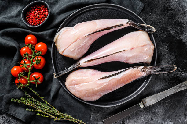 istock Separate fresh monkfish without head and skin. Black background. Top view 1254304000