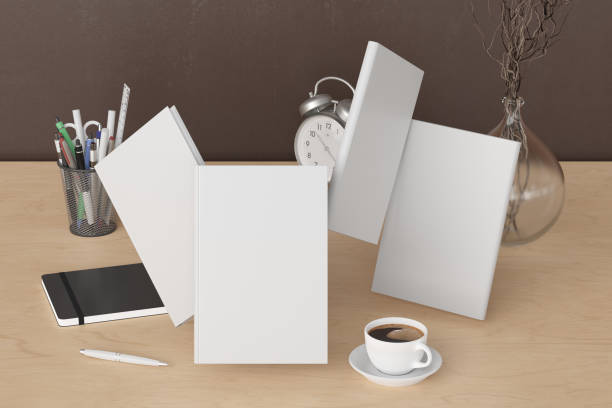 istock Blank book cover mock up flying over desk in office workspace. 1254305411
