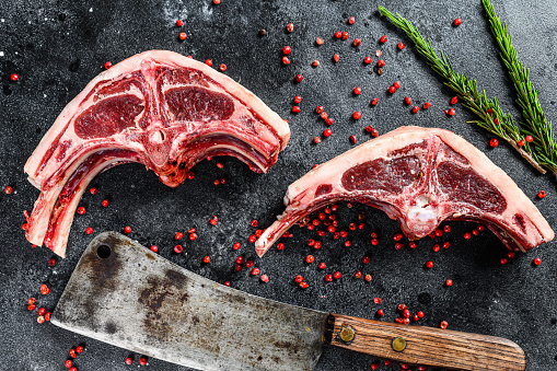 Raw lamb cutlets fresh cut with meat cleaver. Black background. Top view.