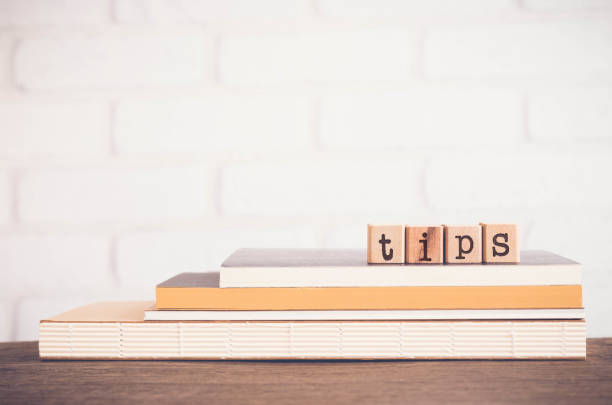 The word TIPS, letters and copy space background, vintage. The word TIPS, letters on wooden block cubes on top of books and table with white bricks background, blank copy space, vintage minimal style. Concepts of tricks, hack, help, guideline, useful hint. tips tricks stock pictures, royalty-free photos & images