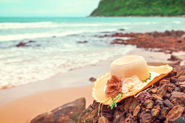 Vintage hat on stone in tropical beach.