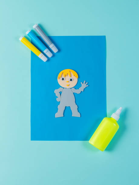 istock A paper man with glue and markers on a blue background. 1254324128
