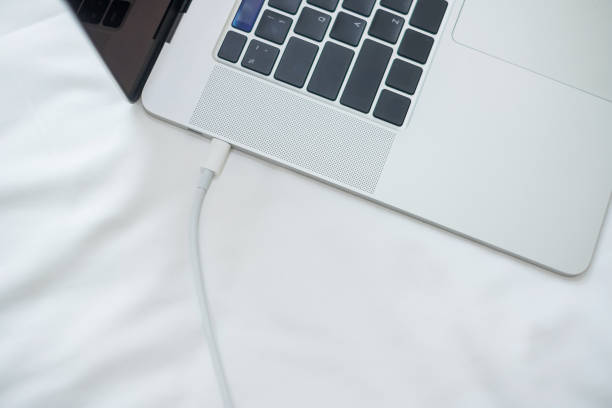 Computer laptop charging battery on bed in the bedroom at home. Technology, multiple sharing charger and lifestyle concepts