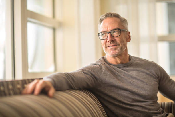 istock Portarit of a handsome older man sitting on a sofa. 1254330043