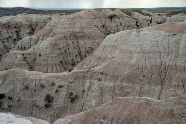 туристы позируют для фотографий, стоя на опасной скале - badlands prairie landscape badlands national park стоковые фото и изображения