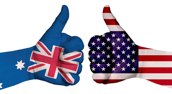 The concept of strengthening the relationship of nations. Two hands are painted with flags of different countries, with a thumb raised up. Australia and the USA