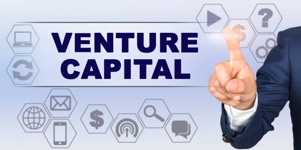 Businessman touching virtual screen with his finger. Screen caption - VENTURE CAPITAL