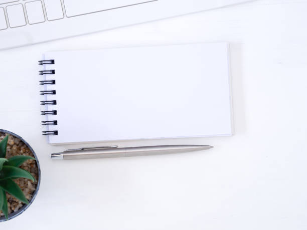 istock Top view, flat lay notebook and pen with the keyboard on modern white desk, business concept with space for your text. 1254333426