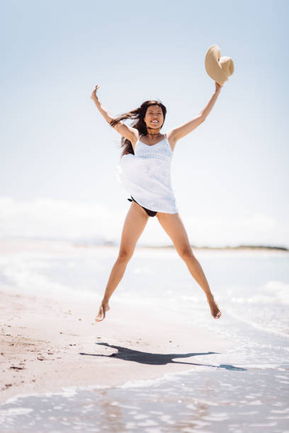 mujer de la felicidad saltando en la playa - jumping freedom women beach fotografías e imágenes de stock