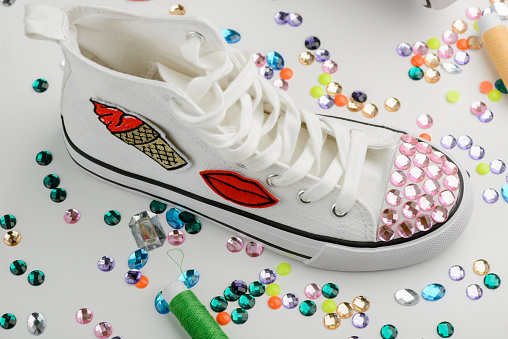 White sneaker decorated with pink rhinestones and embroidered badges