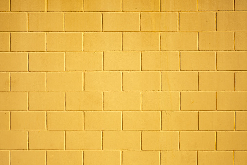Concrete brick wall  painted in yellow color,  full frame view suitable for construction or architecture background, horizontal view. Galicia, Spain.