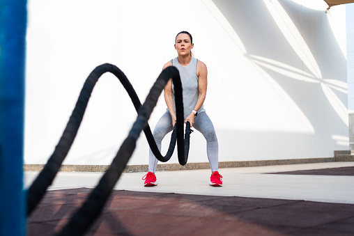 Woman doing Battle Rope exercise for a fit body outdoors