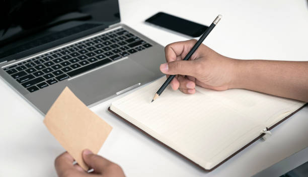 istock Cropped shot of man hand using pencil writing on blank notebook while sitting at office desk. 1254360601