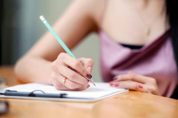 istock female hand writing on chart board with pencil while sitting at wooden table. 1254362392