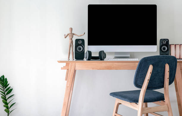 istock Mockup desktop computer with black screen with speakers and headphone on wooden table in contemporary room or studio. 1254362505