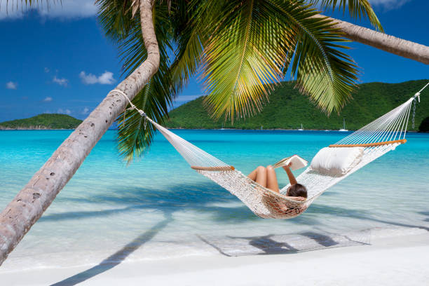 istock woman reading and relaxing in hammock on tropical beach 1254369831