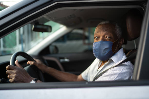 Portrait of senior african man driving a car with face mask Portrait of senior african man driving a car with face mask taxi driver photos stock pictures, royalty-free photos & images