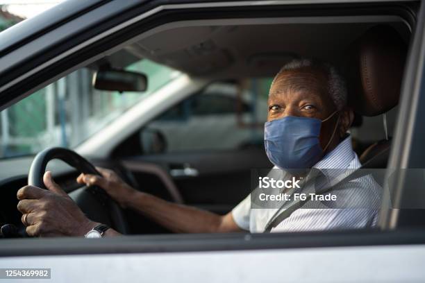 Portrait Of Senior African Man Driving A Car With Face Mask Stock Photo - Download Image Now