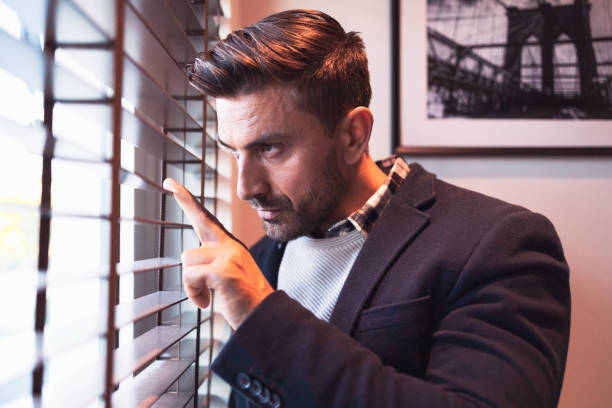 istock Portrait of a caucasian man looking through window blinds 1254372761
