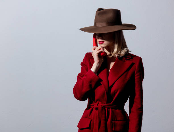 istock Blonde girl in red coat and vintage hat with dial handset 1254373692