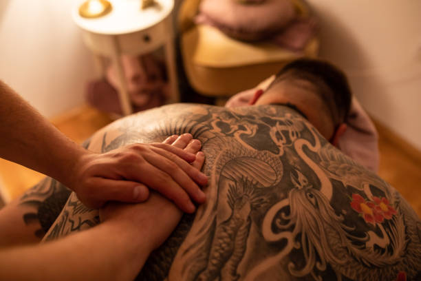 A big guy with a full back tattoo getting his back massaged stock photo