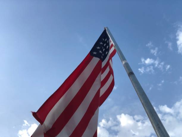 istock United States flag on a pole with blue sky and clouds 1254386491