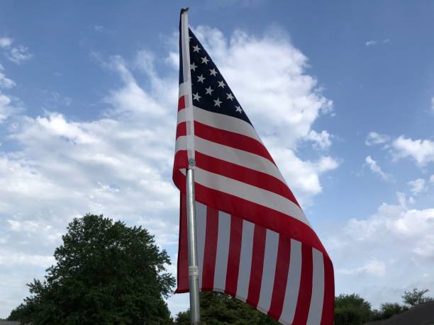 istock United States flag on a pole with blue sky and clouds 1254386503