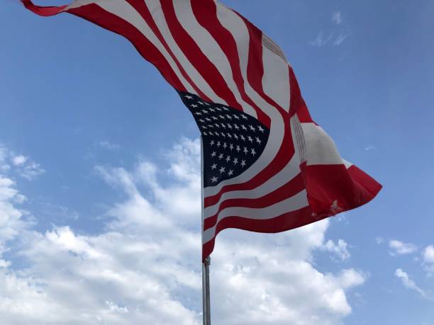 istock United States flag on a pole with blue sky and clouds 1254386561