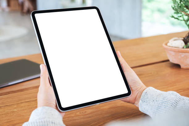 istock a woman holding black tablet pc with blank white screen on wooden table 1254389195