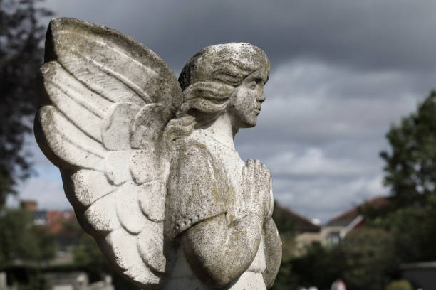 istock Cemetery angel statues in sunshine after rainstorm dark clouds 1254396021