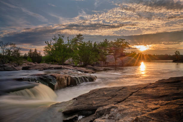 Starburst sunrise Burleigh Falls A beautiful sunrise at Burleigh Falls Ontario shows a starburst pattern of the sun with some colorful lens flare golden hour photos stock pictures, royalty-free photos & images