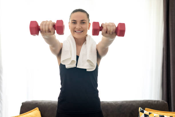 istock Young woman working out with dumbbells at home 1254397351