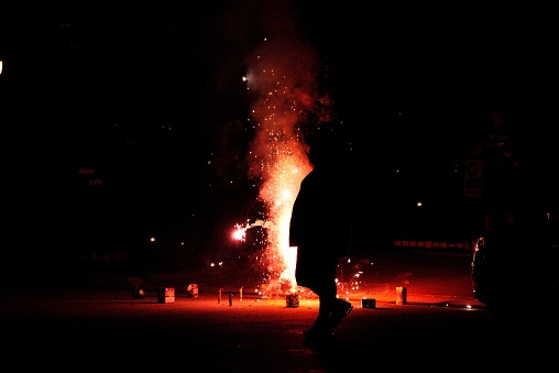 Silhouette of a man watching fireworks on the ground.