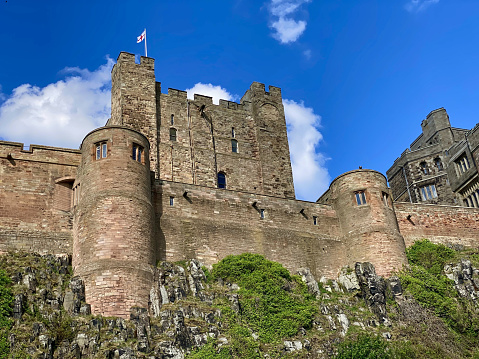 Bamburgh, England, United Kingdom – June 20, 2020: Bamburgh Castle is a medieval castle located on the coast of the North Sea along Bamburgh Beach in the village of Bamburgh. Today the castle is privately owned by the Armstrong family but is open to the public for sightseeing and events.