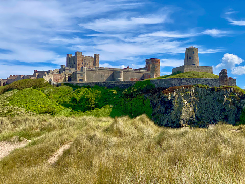 Bamburgh, England, United Kingdom – June 20, 2020: Bamburgh Castle is a medieval castle located on the coast of the North Sea along Bamburgh Beach in the village of Bamburgh. Today the castle is privately owned by the Armstrong family but is open to the public for sightseeing and events.