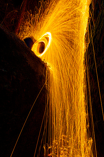 Burning steel wool being used to create beautiful imagery, photographed in a narrow rift