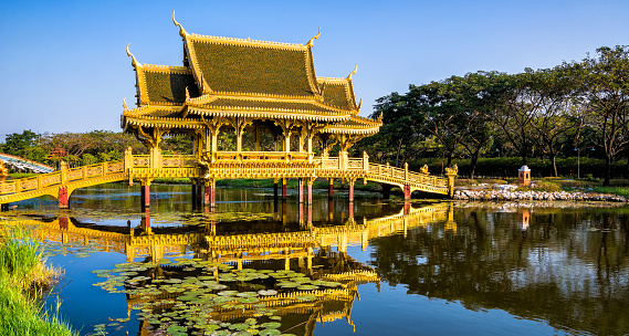 Amazing view of beautiful Golden Bridge and Pavilion of the Enlightened with reflection in the water. Location: Ancient City Park, Muang Boran, Samut Prakan province,  Bangkok, Thailand. Artistic picture. Beauty world. Panorama