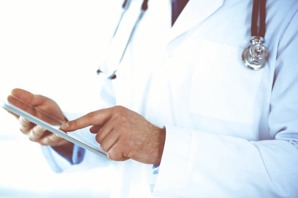 istock Doctor man using tablet computer for network research or virtual disease treatment, hands close-up. Perfect medical service in clinic. Modern medicine, medic data and healthcare concepts. Toned picture 1254408244