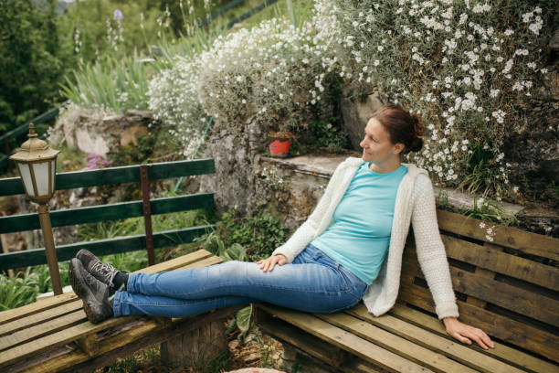 istock Beautiful woman sitting on bench in the yard 1254408501
