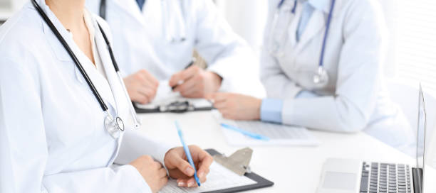 istock Group of unknown doctors discussing problems to stop coronavirus pandemic while sitting at meeting in clinic, close-up . Medicine concept 1254409296