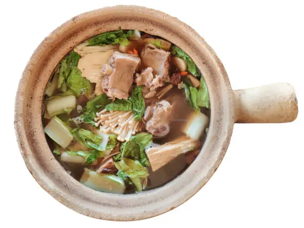Photo of Bak kut teh serving in clay pot, a pork rib dish cooked in broth popularly served in Malaysia and Singapore isolated on white