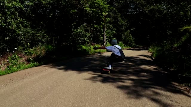 Young adult man ridding skateboard downhill