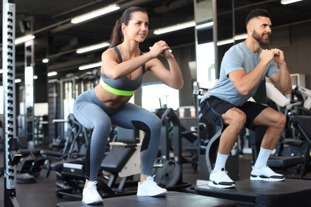 istock Fit couple doing jumping squats in gym gym. 1254417964