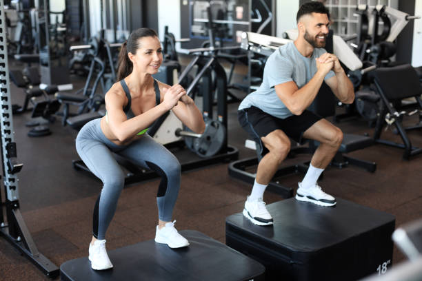 istock Fit couple doing jumping squats in gym gym. 1254418456